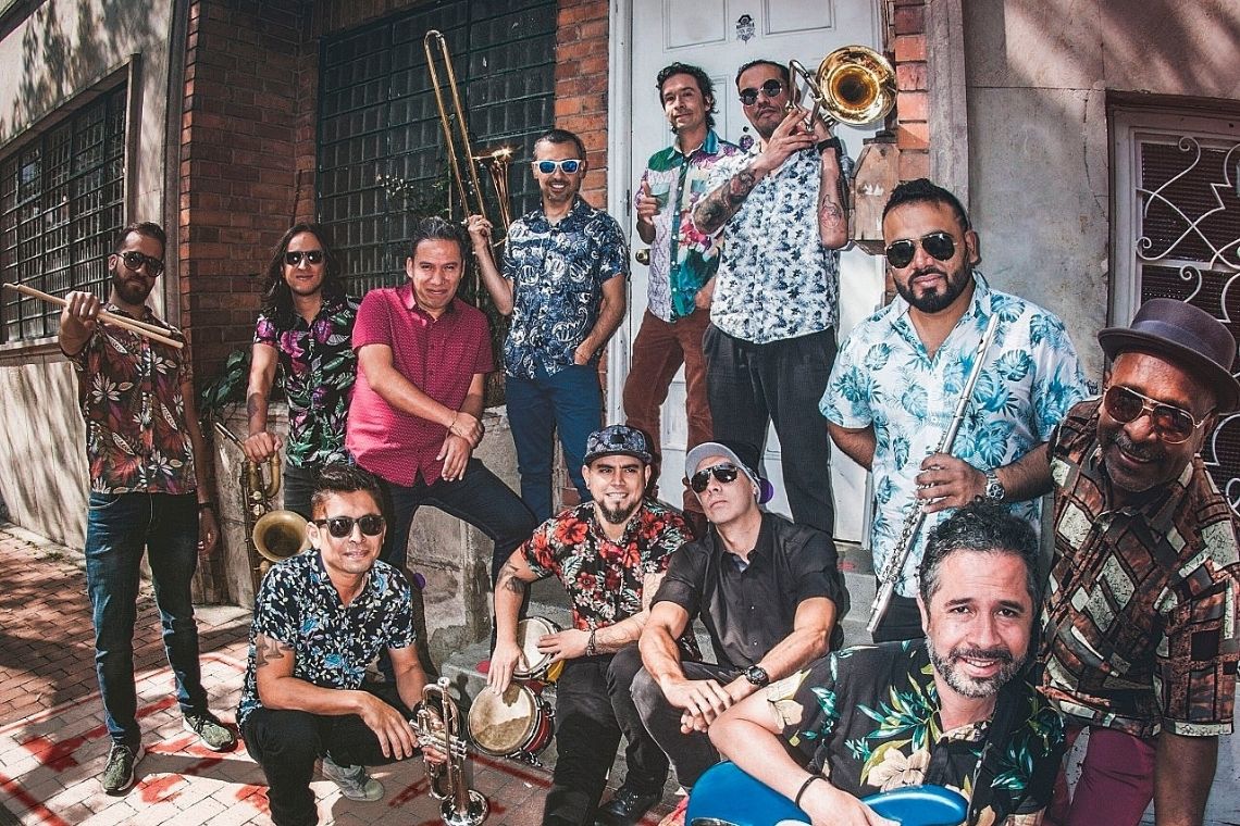 Fotografía de músicos de La 33 Orquesta al frente de una fachada de barrio