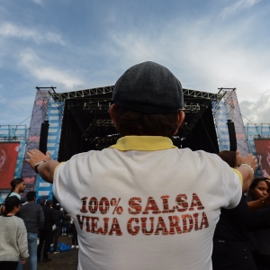 Fotografía del público salsa al parque que muestra la espalda de una persona con camiseta que dice 100 porciento salsa pura
