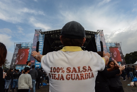 Fotografía del público salsa al parque que muestra la espalda de una persona con camiseta que dice 100 porciento salsa pura